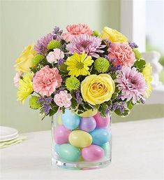 a vase filled with lots of colorful flowers and eggs