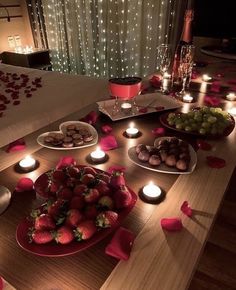 a table topped with plates of food next to candles and hearts on the table top