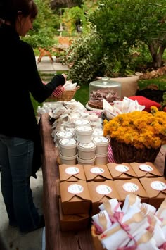 a woman standing next to a table filled with boxes and flowers