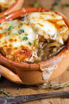 a close up of a casserole in a bowl on a table with utensils