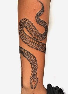 a person with a tattoo on their arm that has a snake in the middle of it