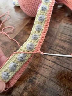 someone is knitting something on top of a table with yarn and crochet needles