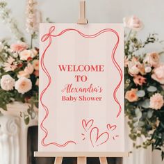 a welcome sign is on an easel in front of some pink and white flowers