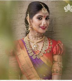 a woman in a sari with jewelry on her neck and chest, posing for the camera