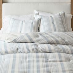 an unmade bed with blue and white striped sheets