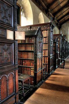 an old library filled with lots of books and wooden benches in the middle of a room