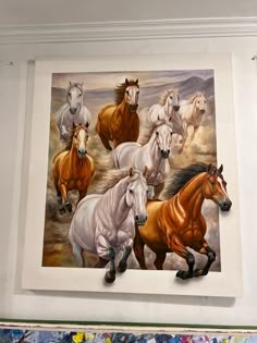 a group of horses running in the wind on a wall with paintbrushes behind it