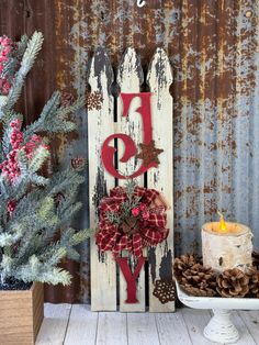 a wooden sign with the word joy on it next to pine cones and a candle