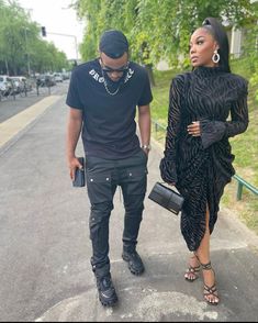 a man and woman are walking down the street wearing all black outfits with high heels