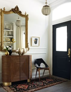 a room with a black door and a mirror on the wall next to a chair