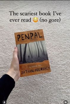 a person holding up a book with the title penpal in front of it