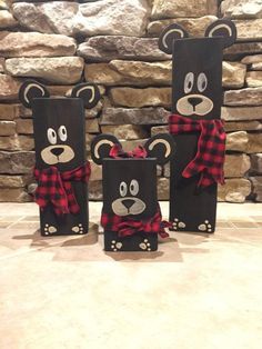 three black paper bags with red and black plaid bows are sitting on a stone floor