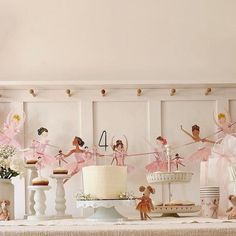 a table topped with cake and cupcakes covered in pink icing next to wall decorations