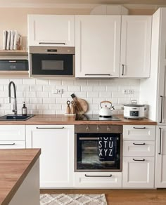 a kitchen with white cabinets and wooden counter tops, including a stove top oven in the center