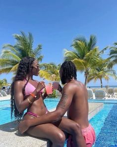 two women sitting next to each other in front of a swimming pool with palm trees