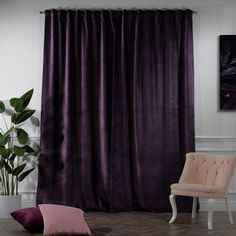 a living room with purple curtains and two chairs in front of the window, next to a potted plant