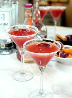 two martini glasses filled with red liquid on a table