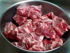 a metal bowl filled with raw meat on top of a table