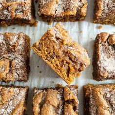 several pieces of cake sitting on top of a white paper covered tray with brownies and powdered sugar