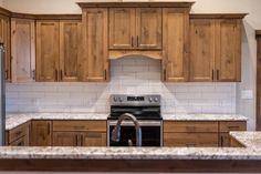 an empty kitchen with wooden cabinets and stainless steel stove top oven in the center island