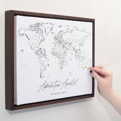 a person holding up a framed map with pins on it