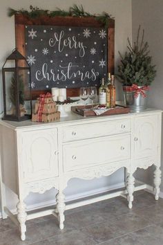 a white buffet table with christmas decorations and a chalkboard on the wall above it