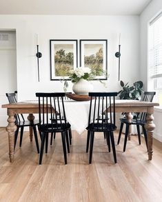 a dining room table with four chairs and a vase on top of the table in front of it