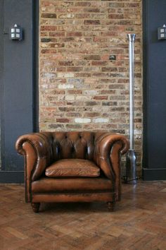 a brown leather chair sitting in front of a brick wall with a red sign that says no 8