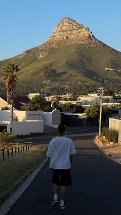 a person is walking down the street with a mountain in the background