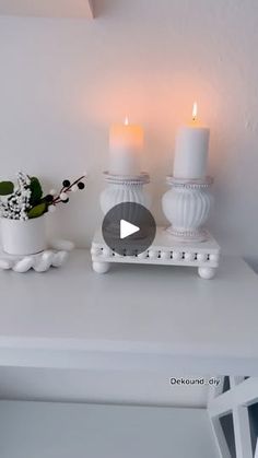 a white table topped with two candles and a potted plant