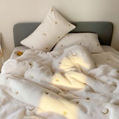 an unmade bed with white sheets and gold stars