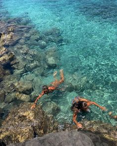 two people are swimming in the clear blue water