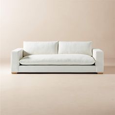 a white couch sitting on top of a wooden floor next to a wall with a light colored background