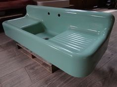 a green sink sitting on top of a wooden pallet next to a couch in a living room