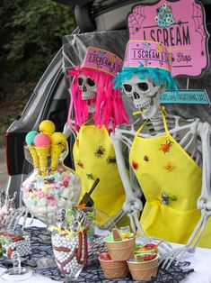 two skeletons dressed in yellow and pink are standing next to an ice cream parlor display