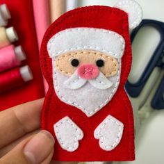 a hand holding up a red santa clause ornament with scissors in the background