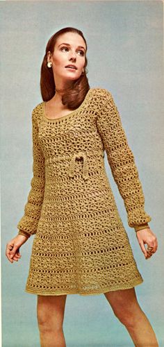 a woman in a crocheted dress poses for the camera with her hands on her hips