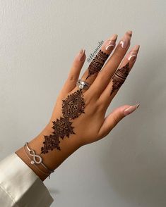 a woman's hand with henna tattoos on it