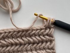 the crochet hook is being used to make a knitted shawl pattern