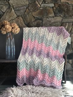 a crocheted blanket sitting next to a vase with flowers