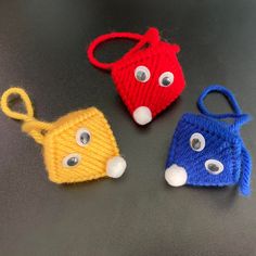 three crocheted bags with eyes and noses are shown on a black table top