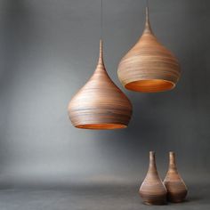 three wooden hanging lights in the shape of tears on a gray background, with one light turned upside down