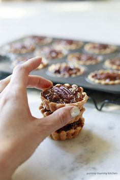 a person is holding some food in front of a muffin tin on a table