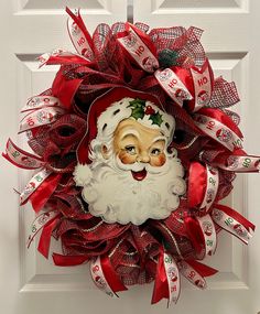 a christmas wreath with santa claus's face and red ribbon on the front door