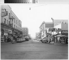 an old black and white photo of a city street with cars parked on the side