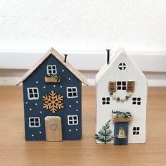 two small wooden houses with snowflakes on them and one has a clock in the middle