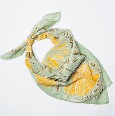 a green scarf with yellow and white designs on it sitting on top of a table