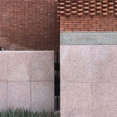 a person sitting on a bench in front of a brick building with grass growing next to it