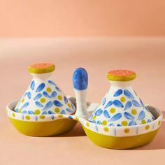 two ceramic bowls with spoons in them on a table