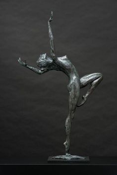 a bronze statue of a woman with her arms in the air and one leg up